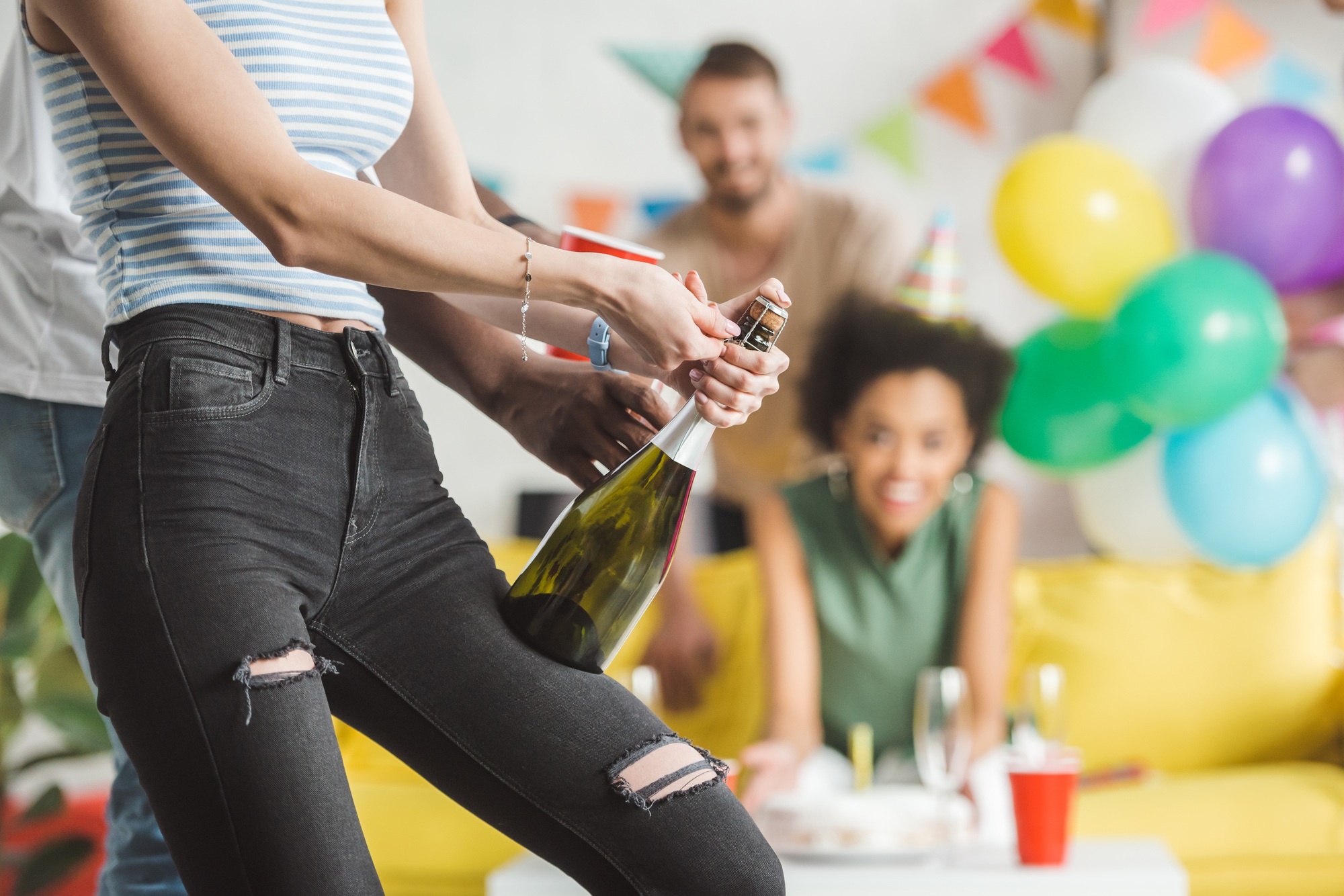 Close-up view of man helping woman opening champagne at birthday party